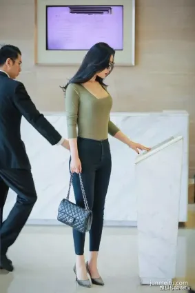 街拍小姐姐身上穿着淺綠色的v領上衣，修身的版型勾勒出優雅的身材